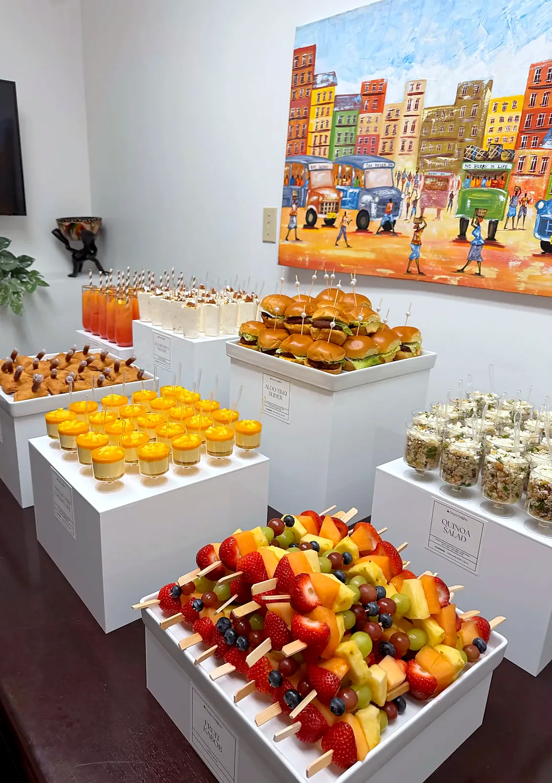 Fruit skewers, sliders and mango dessert cups on white display cubes