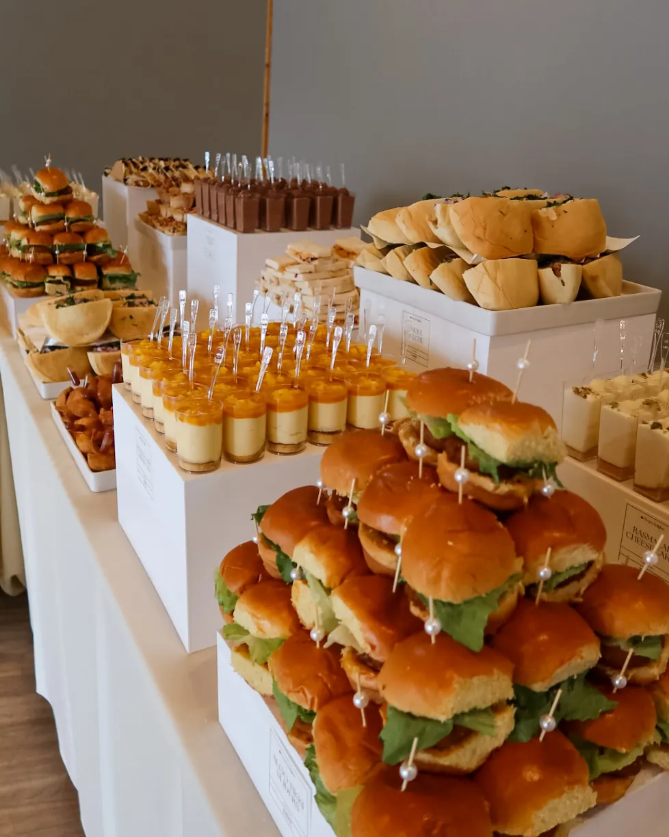 Stacked Indian-fusion sliders and dessert cups on white risers, part of a grazing spread by Deep's Delights