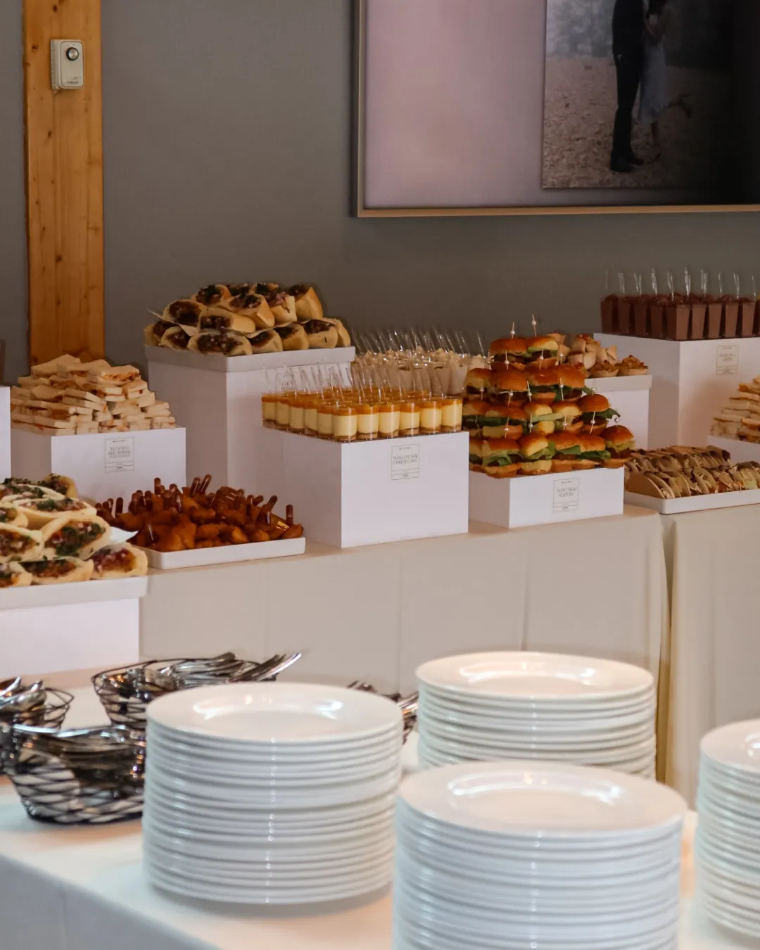 Grazing table of Indian-fusion appetizers and desserts with stacks of plates, styled for a wedding lunch at Azuridge Estate Hotel in Priddis