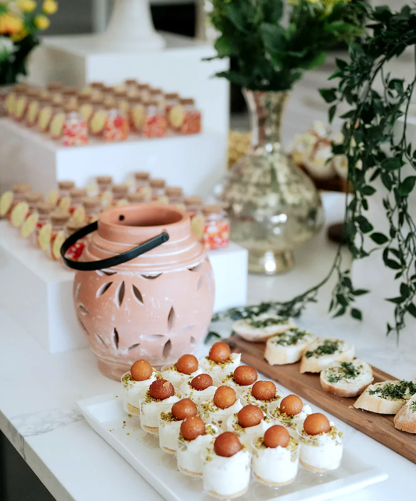 Gulab jamun mousse cups beside a terracotta lantern on a styled dessert display