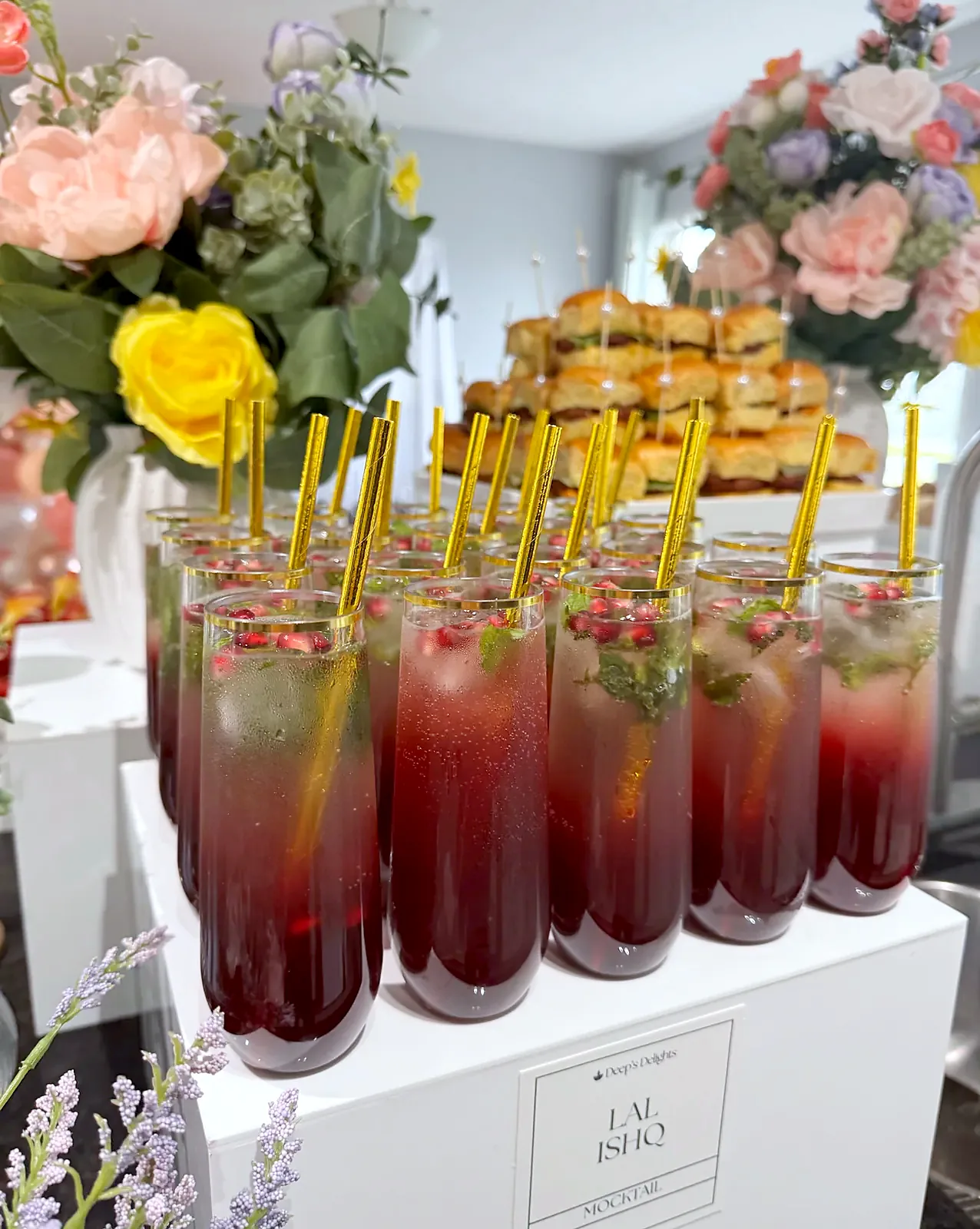 Lal-Ishq mocktails with pomegranate and mint and gold straws on a white riser, styled by Deep's Delights