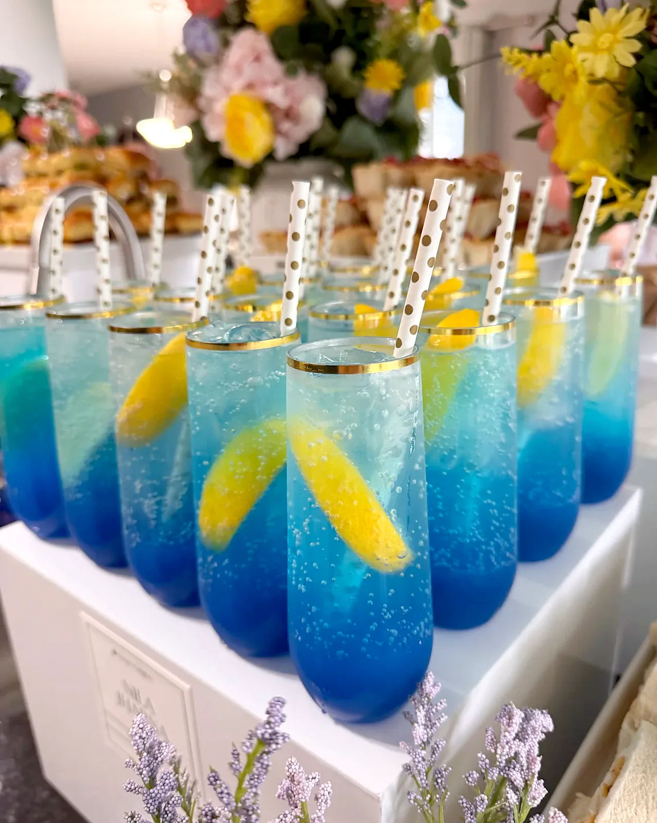 Nila Jharna blue mocktails with lemon slices and polka-dot straws on a styled display