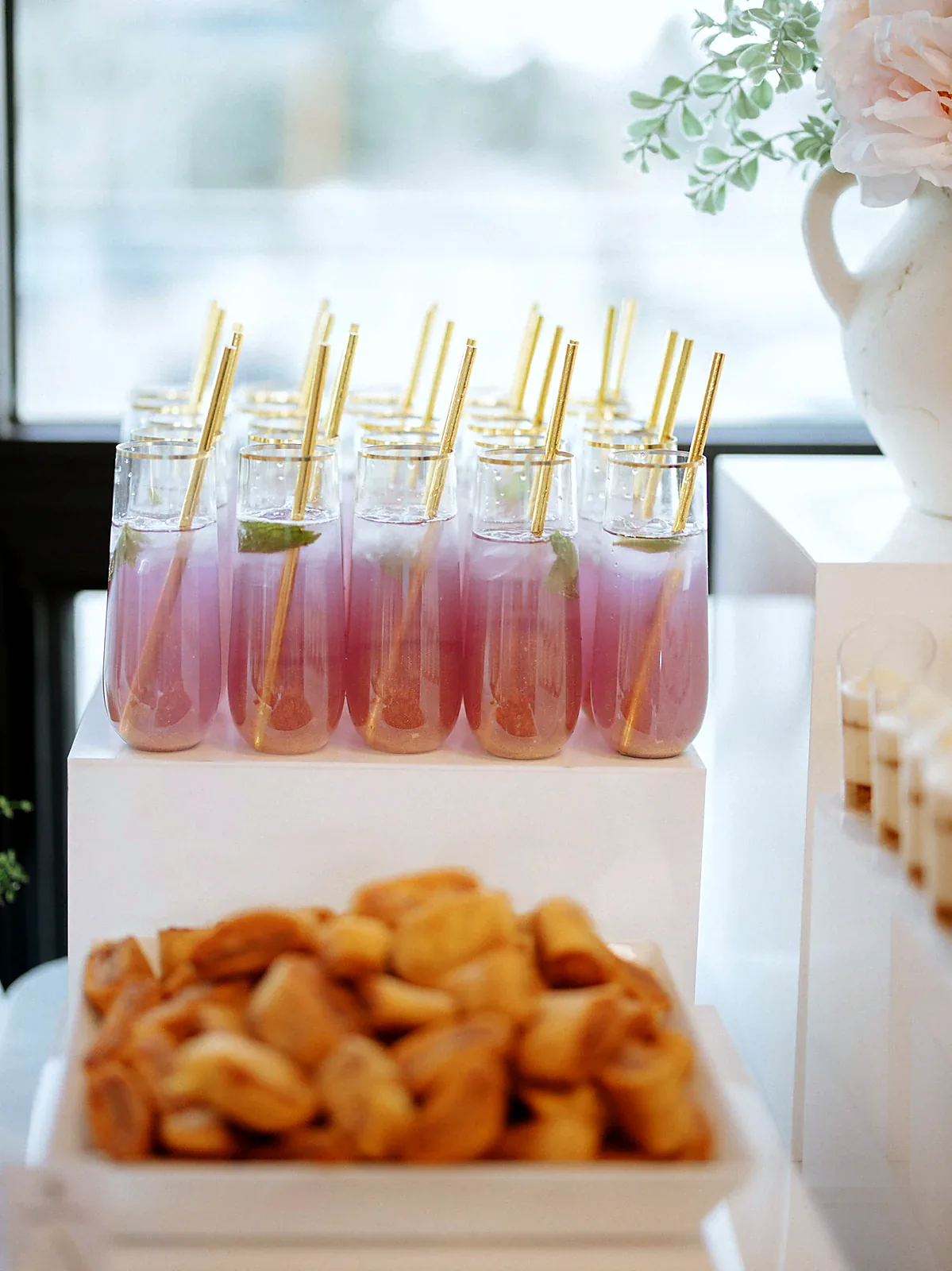 Pink mocktails with gold straws on a styled display